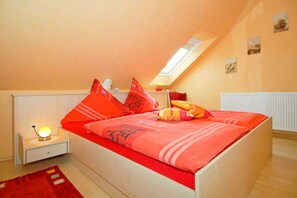 Un dormitorio con cama, mesita de noche, lámpara y una alfombra roja.