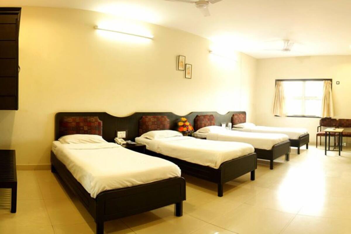 A hotel room with four single beds, a desk, and a chair.