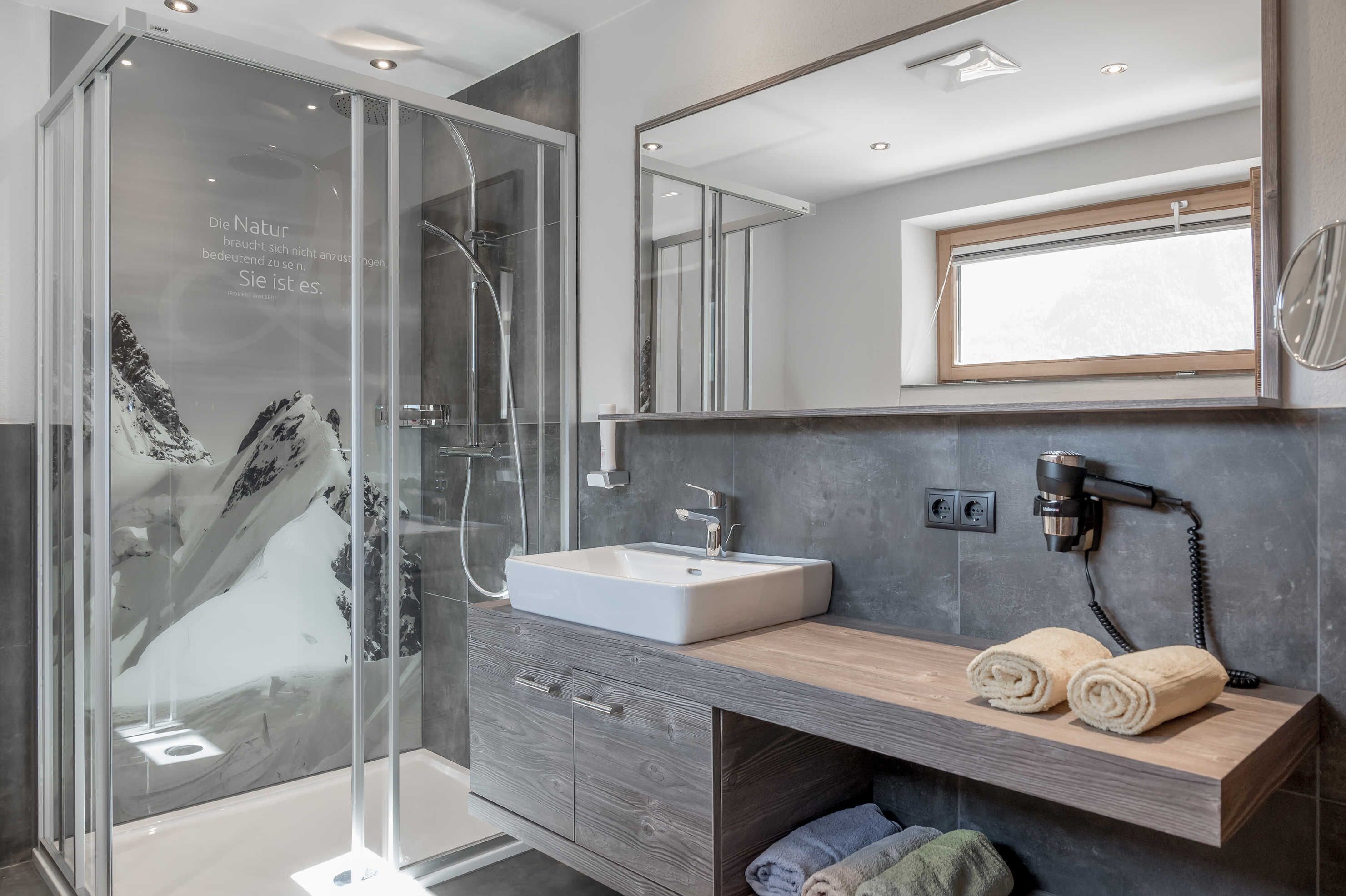 Une salle de bain moderne avec une douche à parois de verre, un lavabo blanc et un meuble-lavabo en bois.