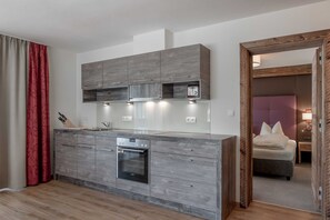A modern kitchen with grey cabinetry, a built-in oven, and a countertop with a knife block. - Apartment Melisande 2 - The Peak Sölden (Sölden)