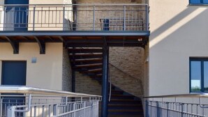 Un paseo marítimo de madera que conduce a un edificio con una escalera cubierta y un balcón.