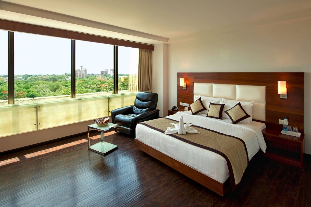 Una habitación de hotel con una cama grande, una silla, una mesita y vistas a la ciudad.