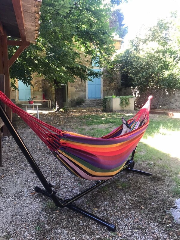 Una silla hamaca con tela colorida, colocada sobre grava al aire libre.