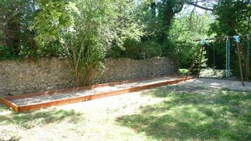 Eine Steinsichtmauer, eine Holzbank und eine Schaukel im Garten.