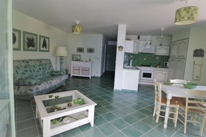 Uma sala de estar com sofá, mesa de centro e área de jantar com cadeiras e mesa.