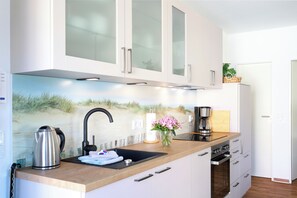 A modern kitchen with a built-in sink, stainless steel kettle, and a coffee maker.