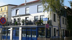 Ein Gebäude mit blauer Fassade, mehreren Fenstern und Balkonen.