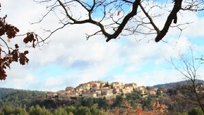 Un'area pranzo esterna rustica con tavolo e sedie, affacciata su un villaggio collinare.