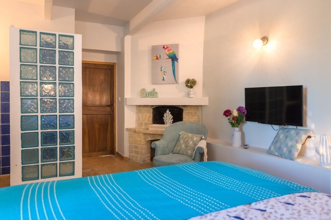 Een slaapkamer met een bed, een open haard, een televisie en een muur met een lijstwerk.
