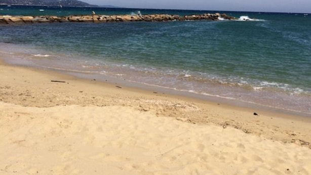 Une plage de sable avec une digue rocheuse et une mer calme.