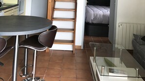 Un espace de vie compact comprenant une cuisine, un coin repas et un escalier menant à une chambre en mezzanine.