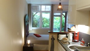 A compact kitchen with a small dining area, a window with a view of greenery, and basic amenities. - Studio in Didier FORT DE FRANCE (Fort de France)