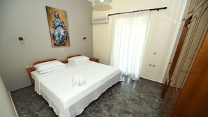 A bedroom with a large bed, a painting on the wall, and a window with curtains. - Platakia Blu (Corfu)
