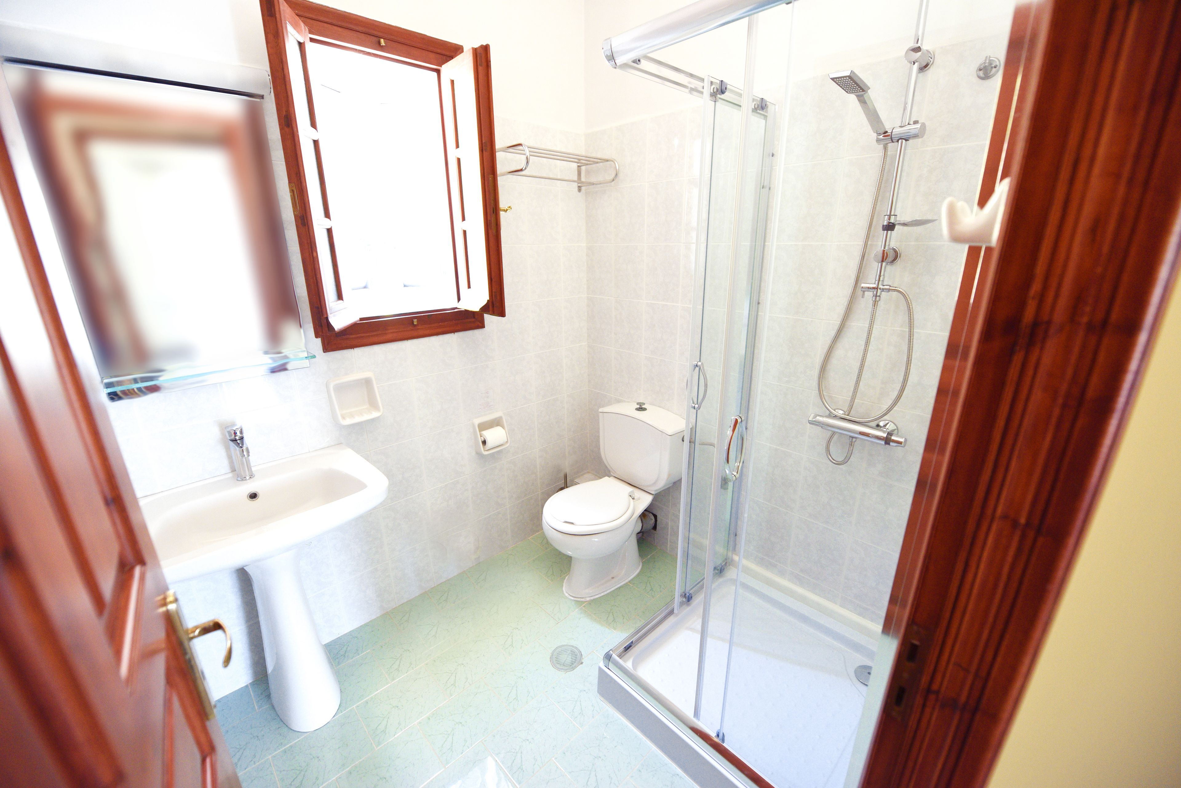 A bathroom with a glass-enclosed shower, a white sink, and a toilet.