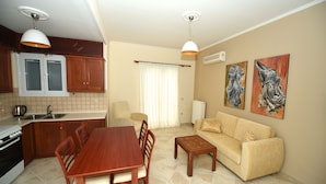 A compact living space with a dining area, kitchenette, sofa, and artwork. - Platakia Blu (Corfu)
