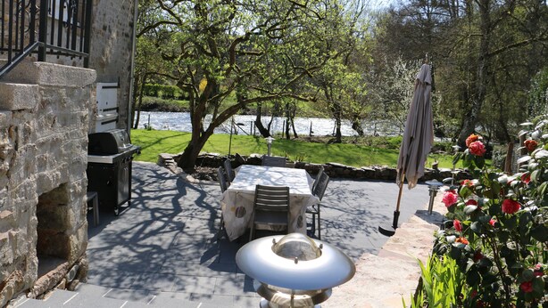 Un patio al aire libre con una parrilla de piedra, una mesa con sillas y una lámpara decorativa.