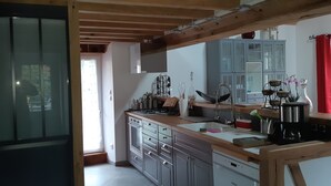 Una cocina con vigas de madera, estufa, armarios y un lavamanos.