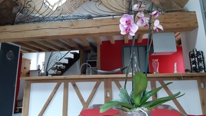 Techo de madera con barandilla metálica decorativa, una escalera y una pared roja al fondo.