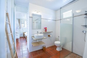 Une salle de bain avec une douche à parois de verre, un lavabo blanc et des toilettes.
