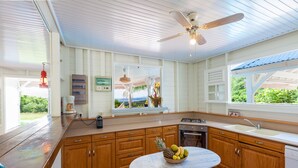 A kitchen with wooden cabinets, a marble countertop, a gas stove, a sink, and a ceiling fan. - Villa Vue Sauvage in Tartane, in the Caravelle nature reserve. (LA TRINITÉ)