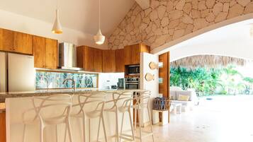 A modern kitchen with a central island, bar stools, and a stone accent wall.