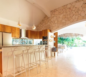Een moderne keuken met een centraal eiland, barkrukken en een accentmuur van steen.