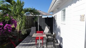 Une terrasse avec une table et des chaises, entourée d’une plateforme en bois et d’un bâtiment blanc.