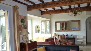 Un salon avec un canapé bleu foncé, une table basse en bois et un lustre.