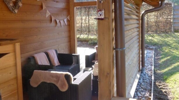 A cozy wooden cabin with a sofa and a bed, a fireplace, and a view of the outdoors.