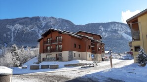 Un edificio de varios pisos con balcones, una base de piedra y suelo cubierto de nieve.