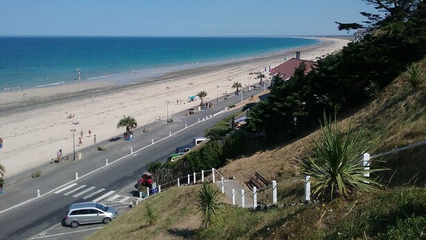 A coastal road with a beach and ocean in the background. - Beautiful duplex near the sea (the islands) (Donville-les-Bains)