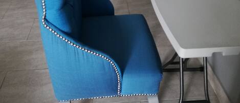 A dining area with blue upholstered chairs, a white table, and a tiled floor.