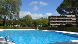 Una piscina con escalera metálica, rodeada de un deck de baldosas blancas.
