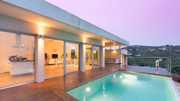 Une maison moderne dotée d’une piscine, de grandes portes vitrées et d’une terrasse.