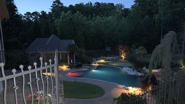 A landscaped outdoor area with a swimming pool, a basketball court, and a well-maintained lawn.