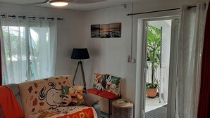 Una sala de estar con un sofá, una lámpara, una mesita y vistas al exterior.