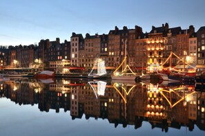 Eine Uferlandschaft mit historischen Gebäuden, einem ruhigen Hafen und beleuchteten Bauwerken.