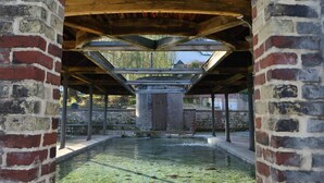 Une structure arquée en briques, dotée d’un plafond en bois et d’une piscine à sa base.