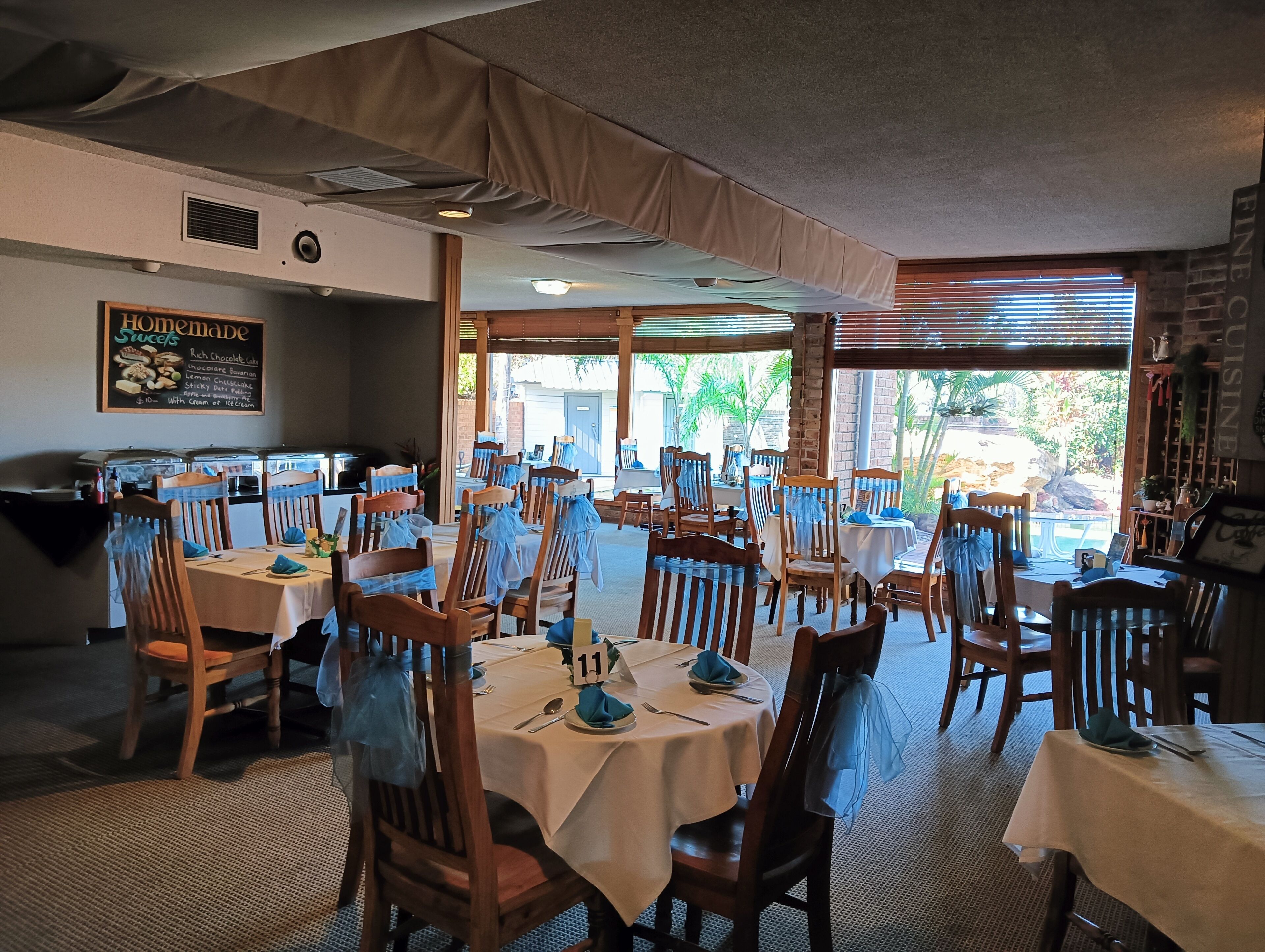 Un restaurant doté de nombreuses tables et chaises, d’un menu écrit à la craie et de grandes fenêtres.