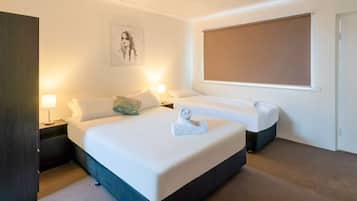 Habitación de hotel con una cama grande, dos mesitas de noche, una ventana y un cuadro en la pared.