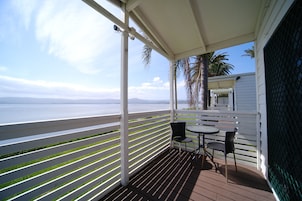 A balcony with a view of the sea, white railings, and two chairs.