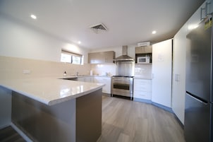 A modern kitchen with a central island, stainless steel appliances, and light wood flooring.