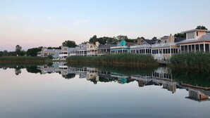 A waterfront property with multiple buildings, including a house with a balcony and a covered area with a view of the water. - Renters paradise in Beachwalk Resort (Michigan City)