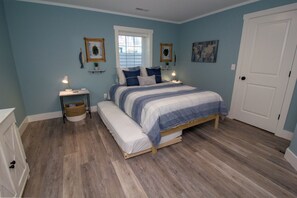 A bedroom with a bed, bedside tables, a bench, and a door. - Renters paradise in Beachwalk Resort (Michigan City)