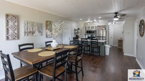 A dining area with a wooden table and chairs, surrounded by artwork and a vase with flowers. - Hidden Hideaway | 4BR Connected Condo Near Silver Dollar City (HH9-3+4) (Reeds Spring)