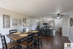 A dining area with a wooden table and chairs, surrounded by artwork and a vase with flowers.