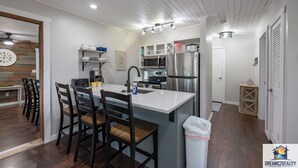 A modern kitchen with a central island, bar stools, a microwave, oven, and a refrigerator. - Hidden Hideaway | 4BR Connected Condo Near Silver Dollar City (HH9-3+4) (Reeds Spring)