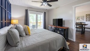 A bedroom with a bed, a ceiling fan, a TV, and a dining area with a table and chairs. - Hidden Hideaway | 4BR Connected Condo Near Silver Dollar City (HH9-3+4) (Reeds Spring)