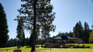 A golf course with a clubhouse, a flag, and a bench. - Lake Almanor West - Lakefront Cabin (Chester)