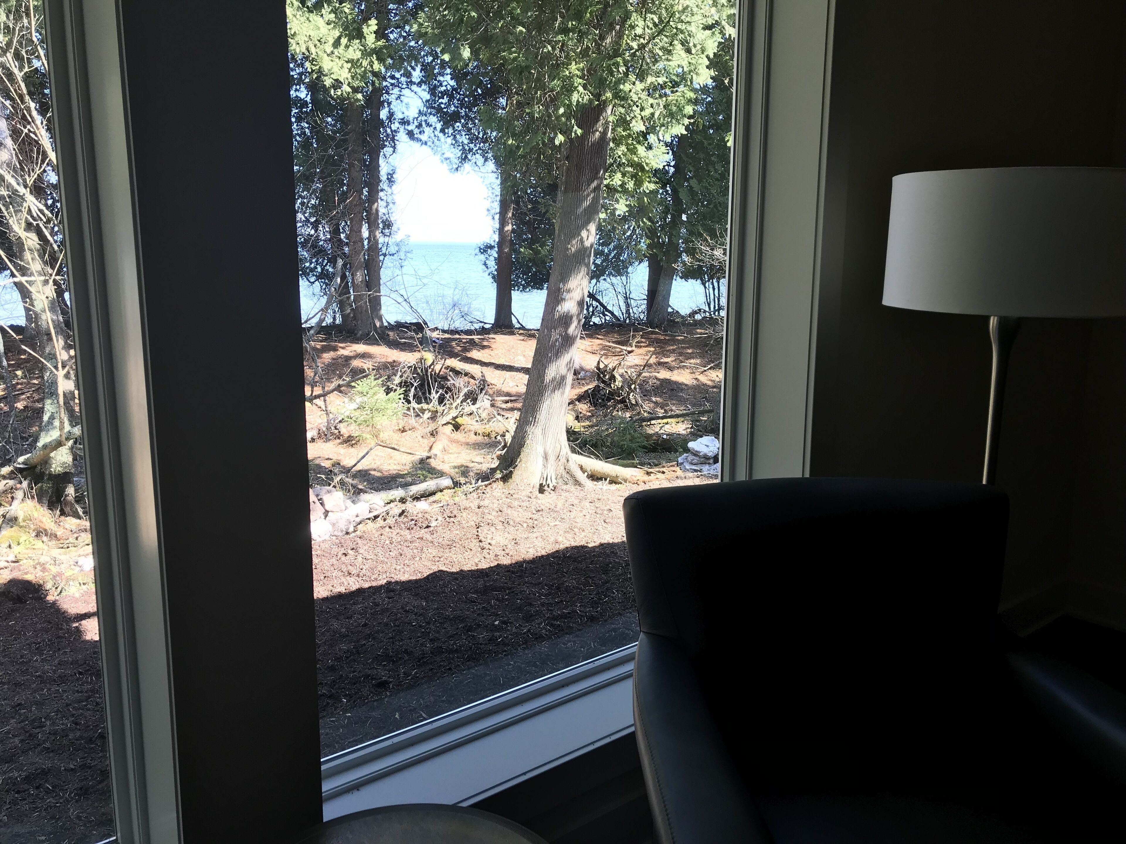 Ein Zimmer mit großem Fenster und Blick auf eine natürliche Landschaft mit Bäumen und einem Gewässer.